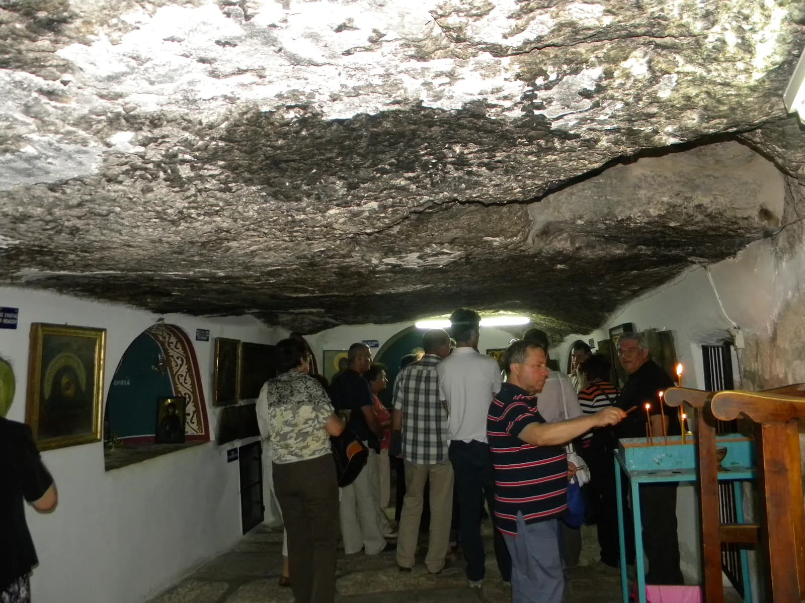 מבקרים בתוך מערת המגושים: תקרת סלע טבעית, קירות מסוידים ואיקונין