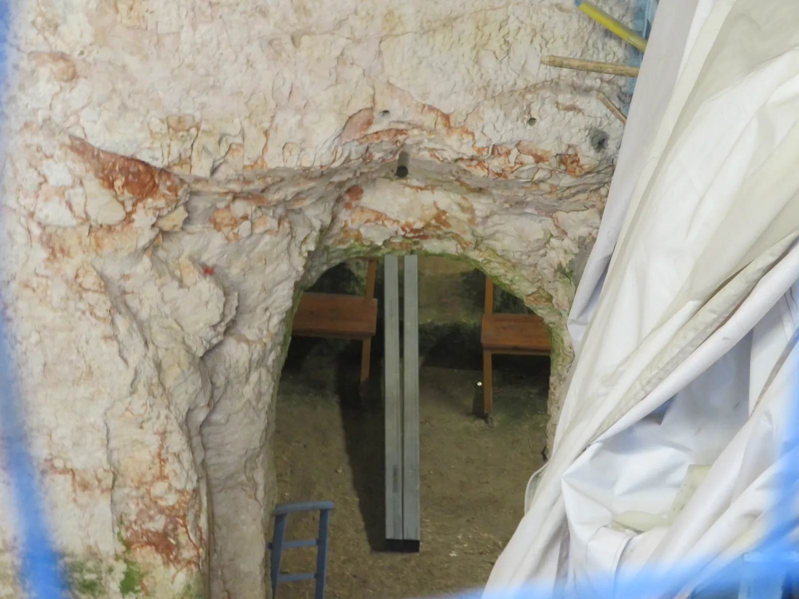 מבט מבעד לשער אל פתח מקומר החצוב בסלע בתוך המערה