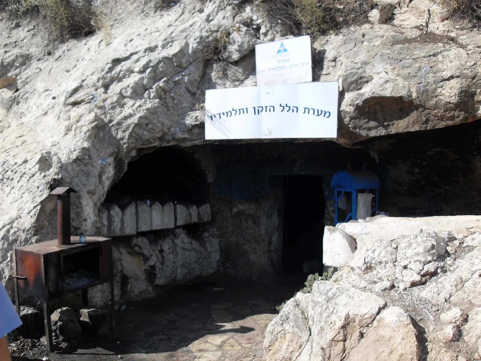 חזית מערת הלל הזקן ותלמידיו במירון, עם השלט והפתח החצוב בצוק