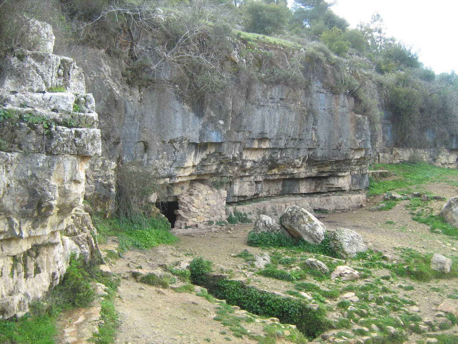 מצוק הגיר באתר עין לימון ופתח חצוב בבסיסו, ולצדו תעלת המים