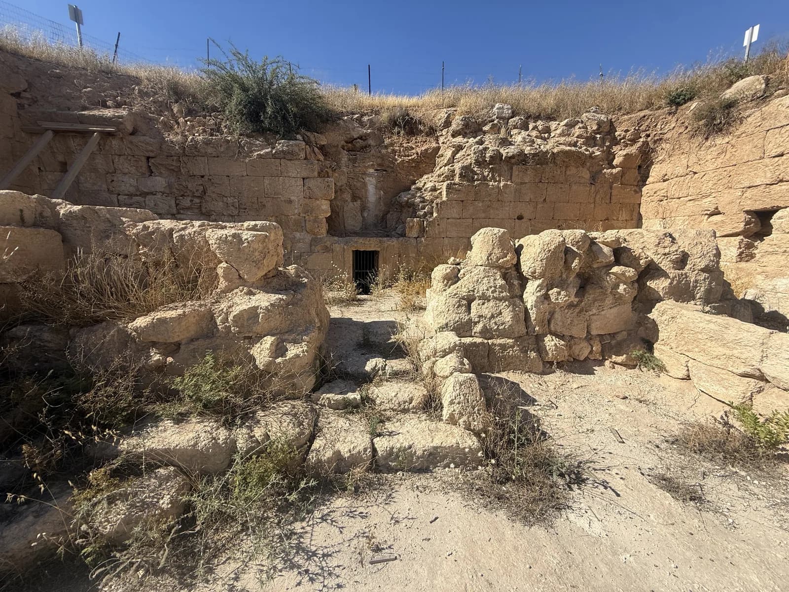 חצר הכניסה החפורה של מערת סלומה וקירות האבן, ובמרכז החזית פתח המערה