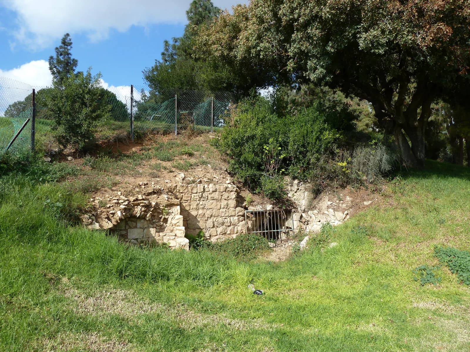 פתח מערת האריה, חסום בסורג, בין קירות אבן בגן העצמאות