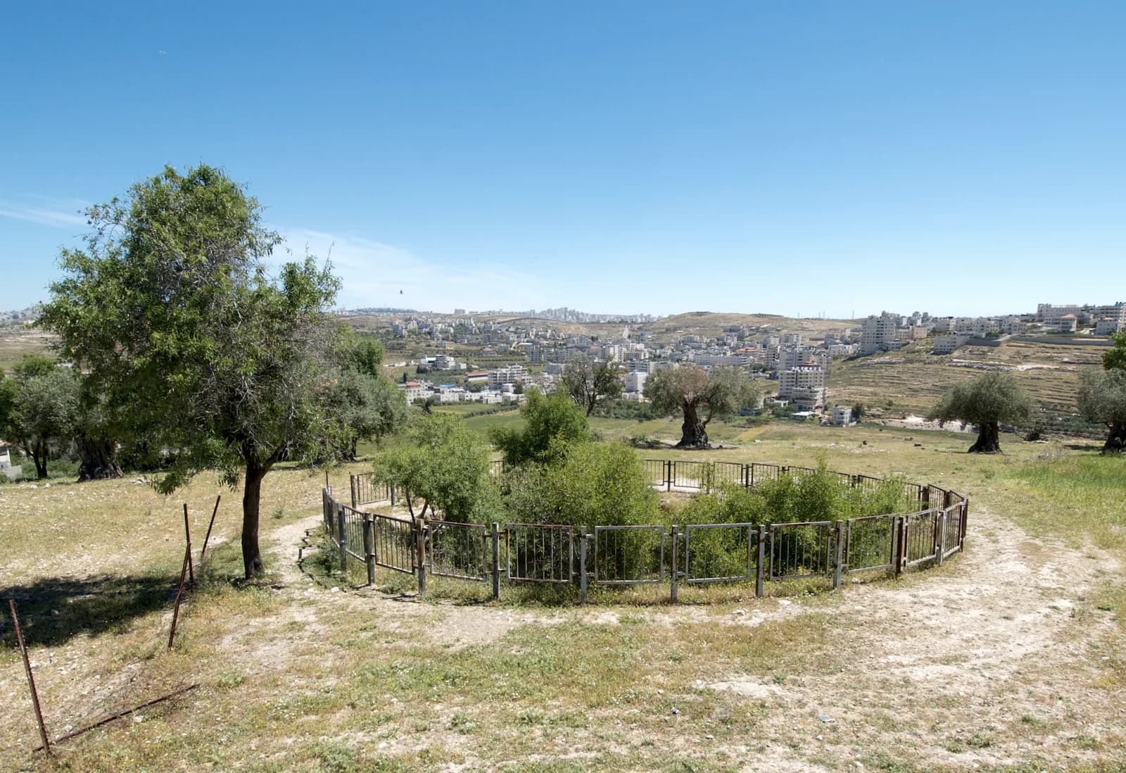 בריכת גבעון המגודרת בשולי אל-ג'יב, ומאחוריה בתי הכפרים שבסביבה