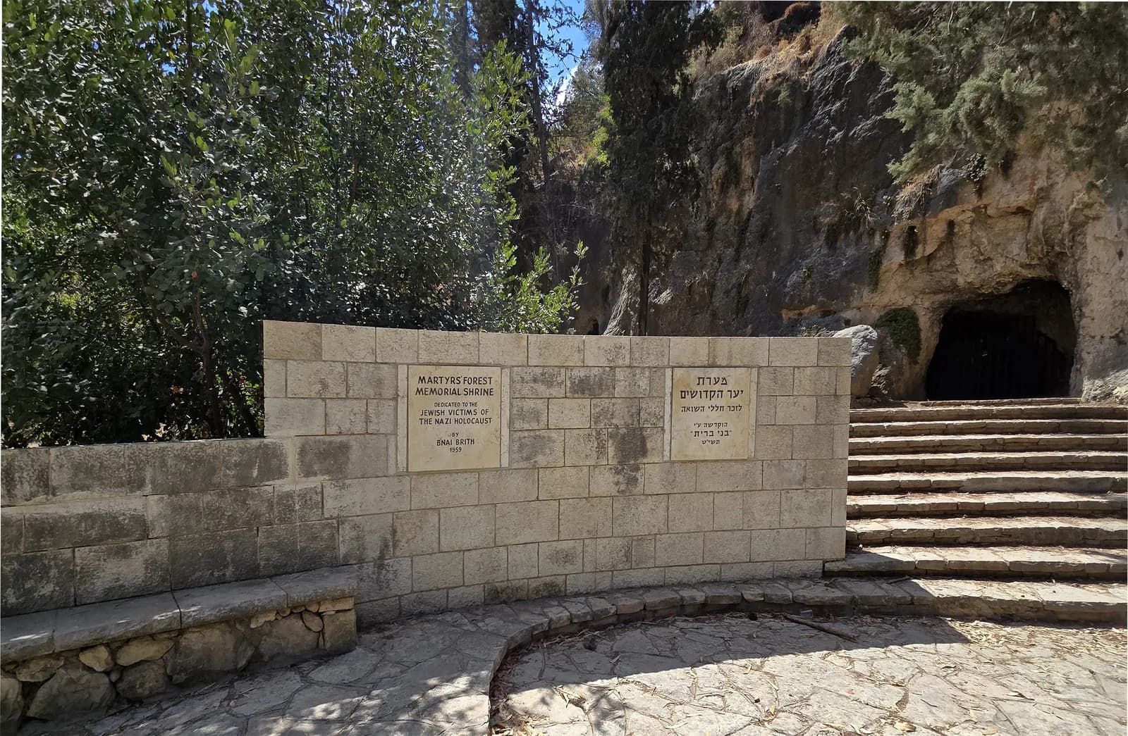 רחבת ההנצחה, שלטי ההקדשה ומדרגות האבן המובילות אל פתח המערה