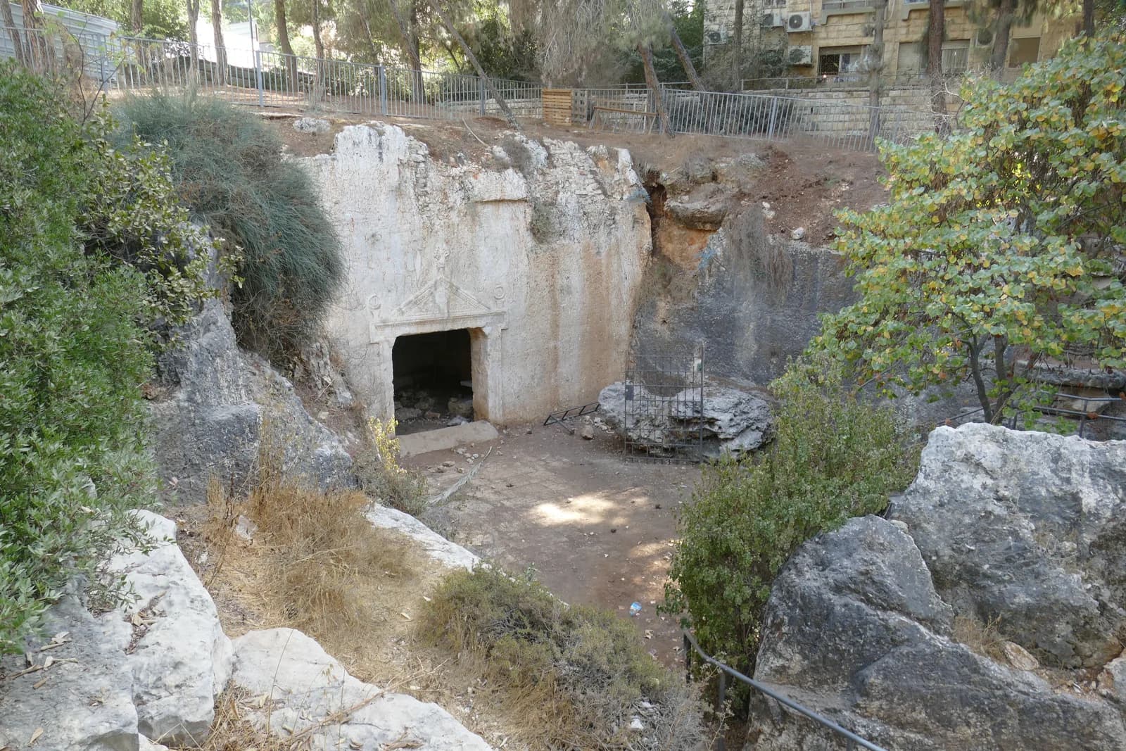 החצר החצובה וחזית מערת האשכולות בתוך הגן, בין בנייני השכונה