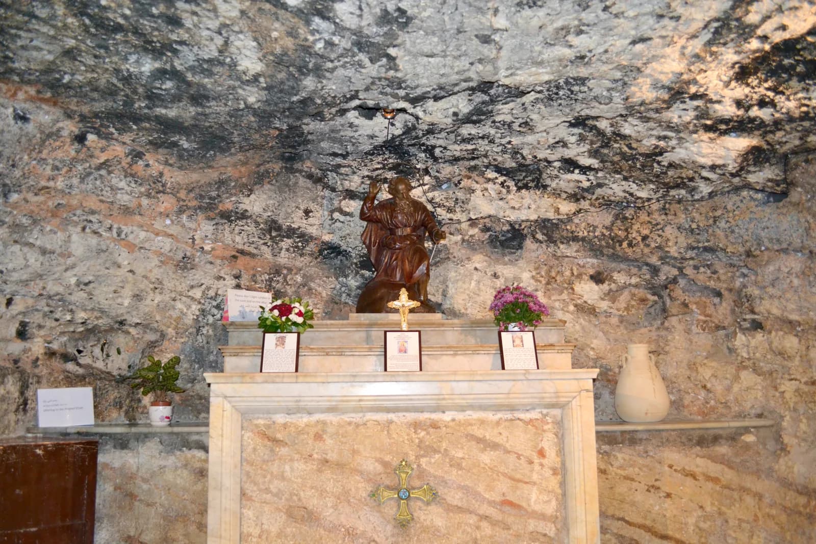 פסל אליהו הנביא על המזבח, על רקע קיר הסלע של המערה