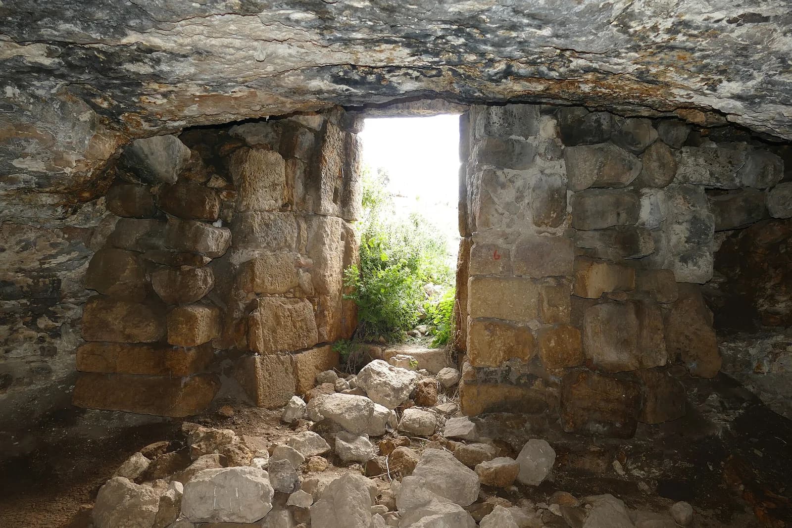 בתוך מערה בחורבת רימון: קיר אבנים בנוי ופתח מלבני המוביל החוצה