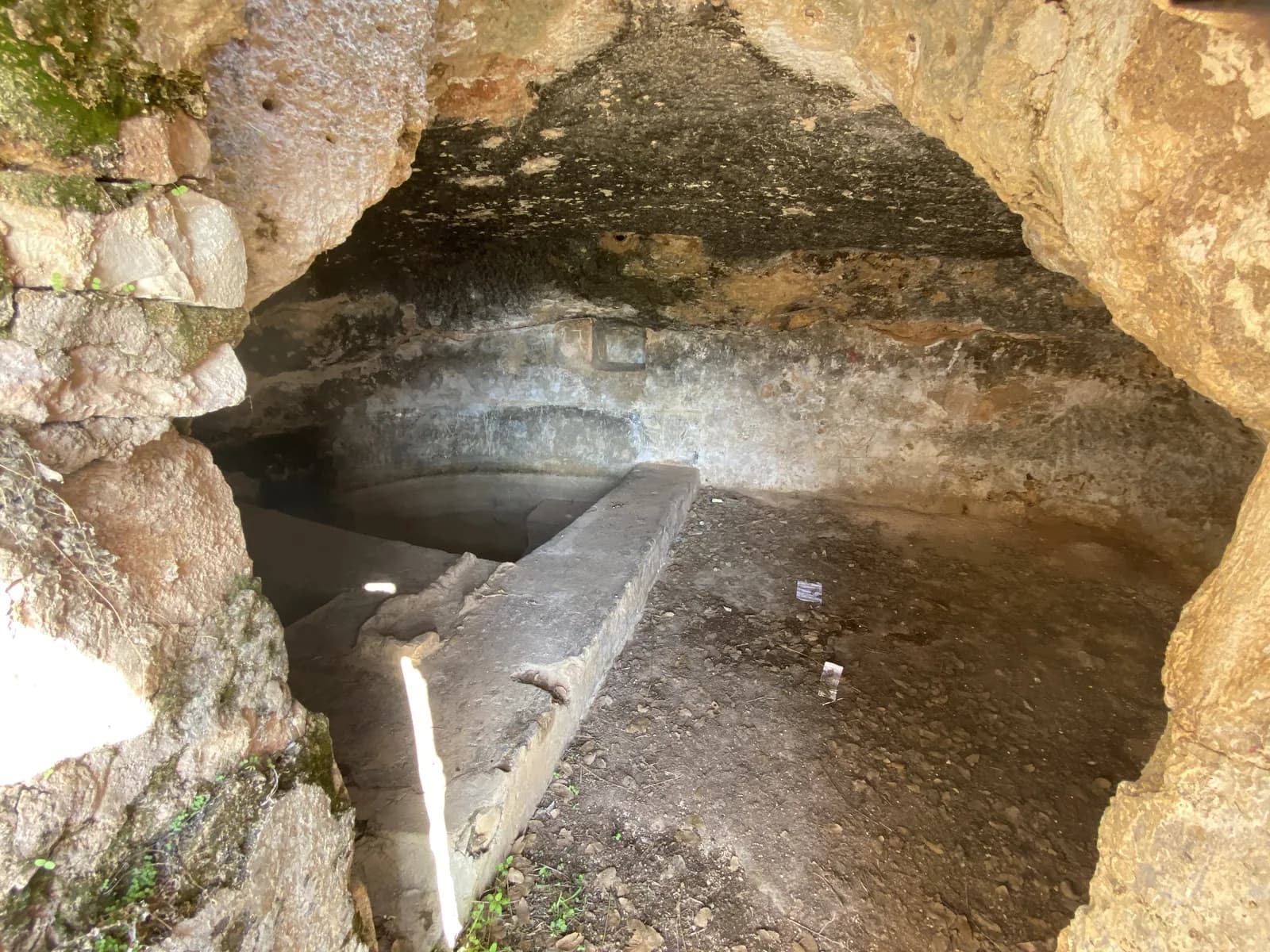 מבט מהפתח אל תוך המערה: בריכת הטבילה החצובה והמעקה הנמוך