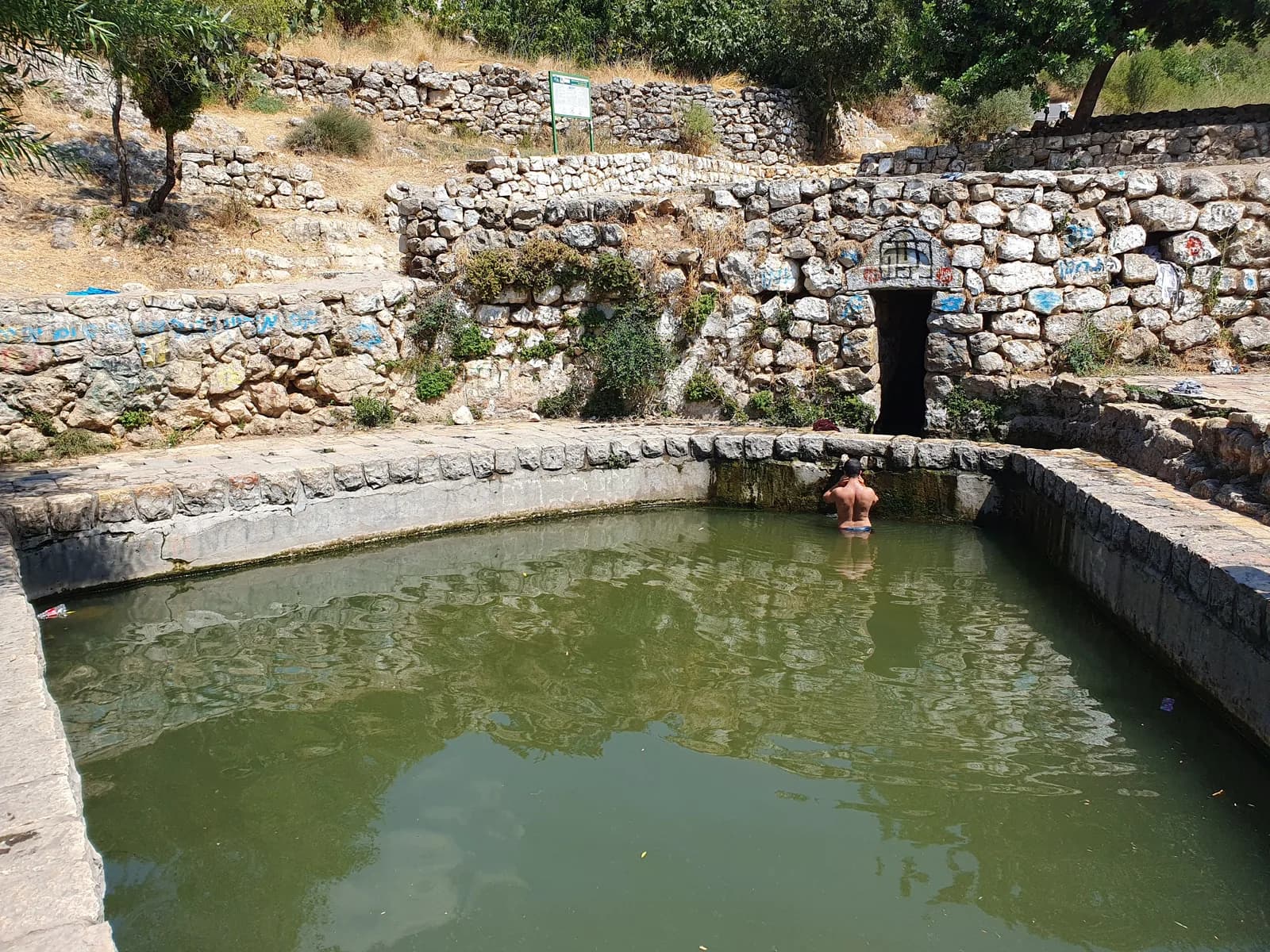 בריכת עין ליפתא ובקיר האבן שמאחוריה פתח נקבת המעיין