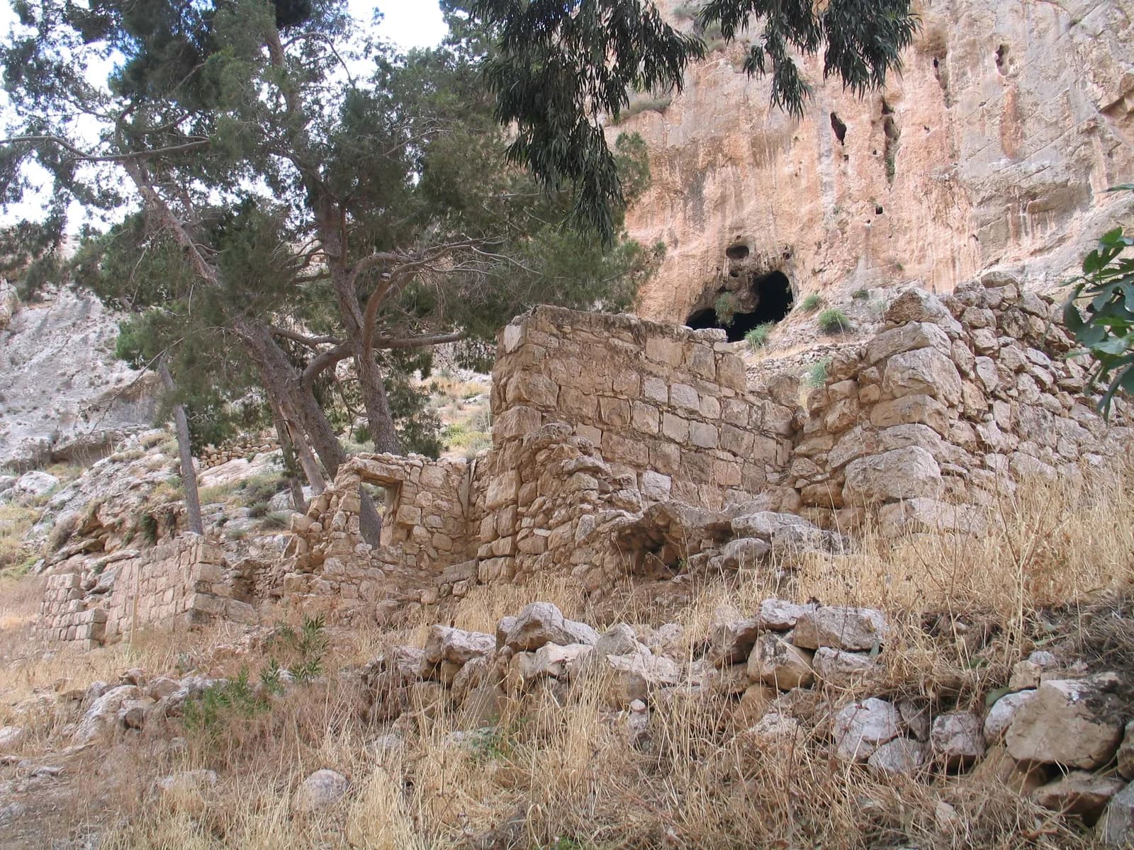 שרידי מבנים בתחום מנזר פרן ומעליהם פתח מערה גדול במצוק