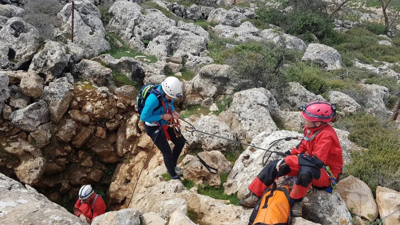 מטיילים עם קסדות בשטח סלעי בדרך למערה