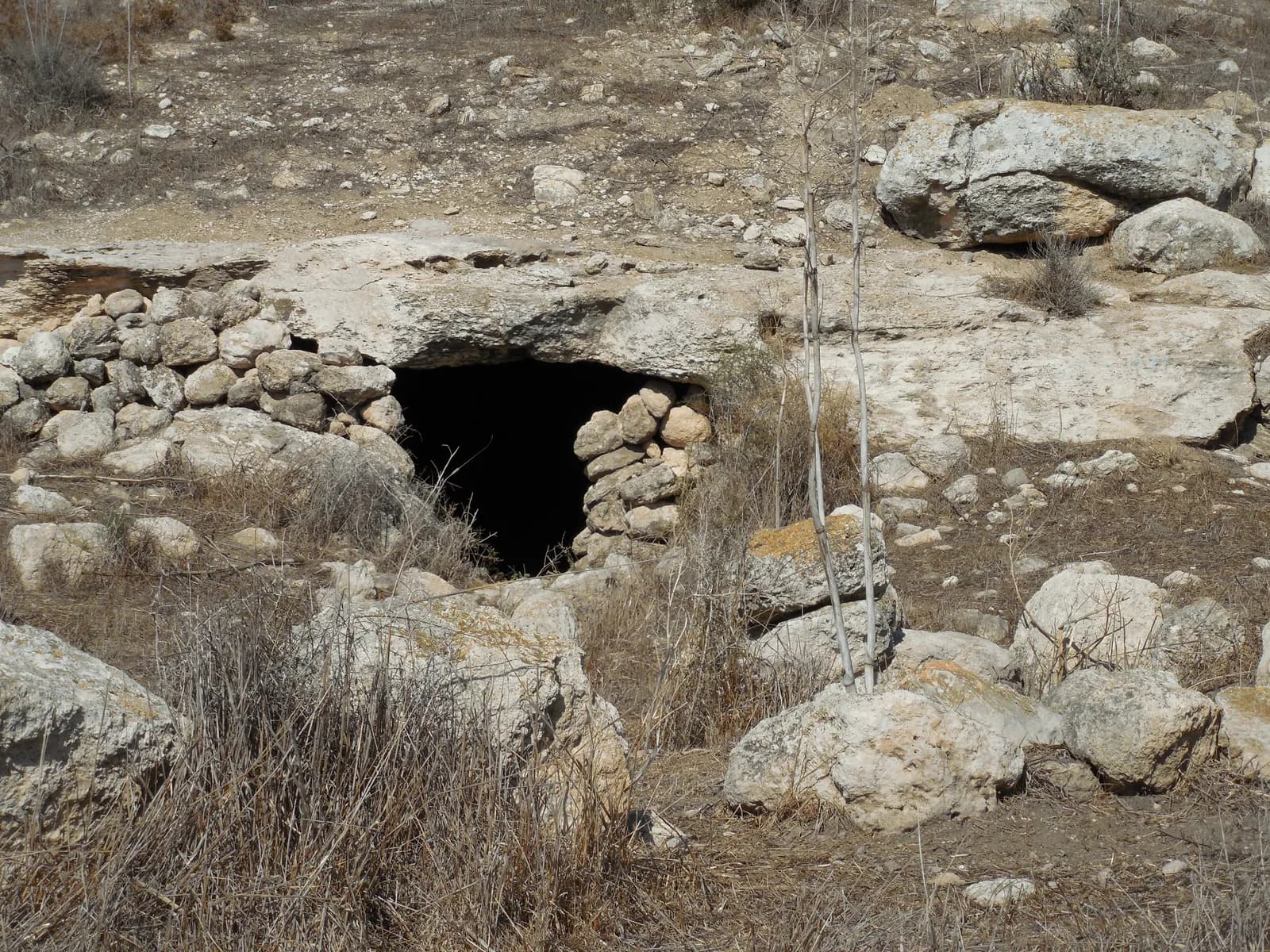 פתח מערה גדולה בין סלעי הגבעה בחורבת לבנין