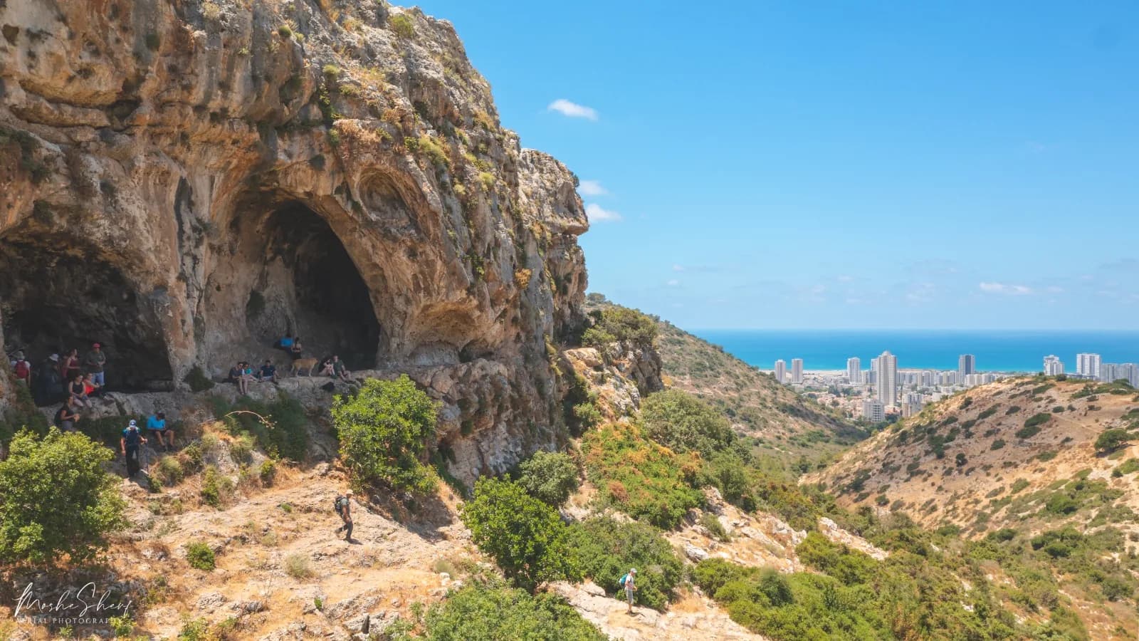 פתחי מערות אורנית במצוק, ובמרחק טירת כרמל והים התיכון