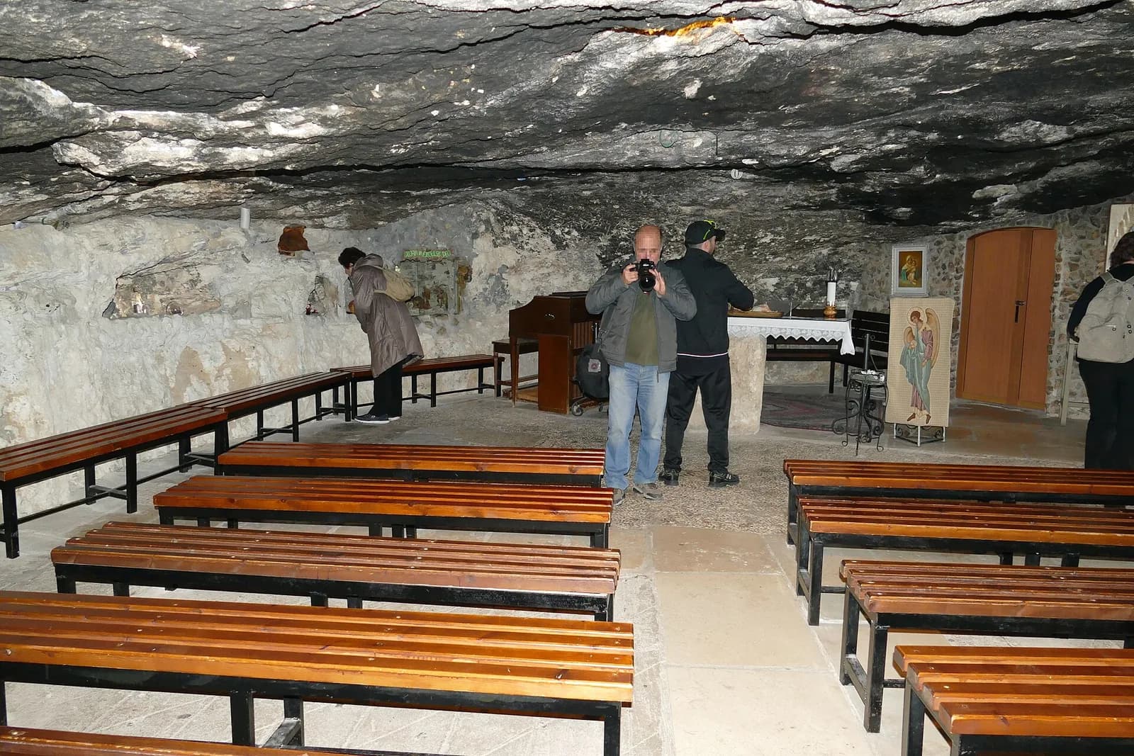 קפלת המערה הגדולה באתר הקתולי בשדה הרועים: תקרת סלע טבעית, ספסלים ומזבח