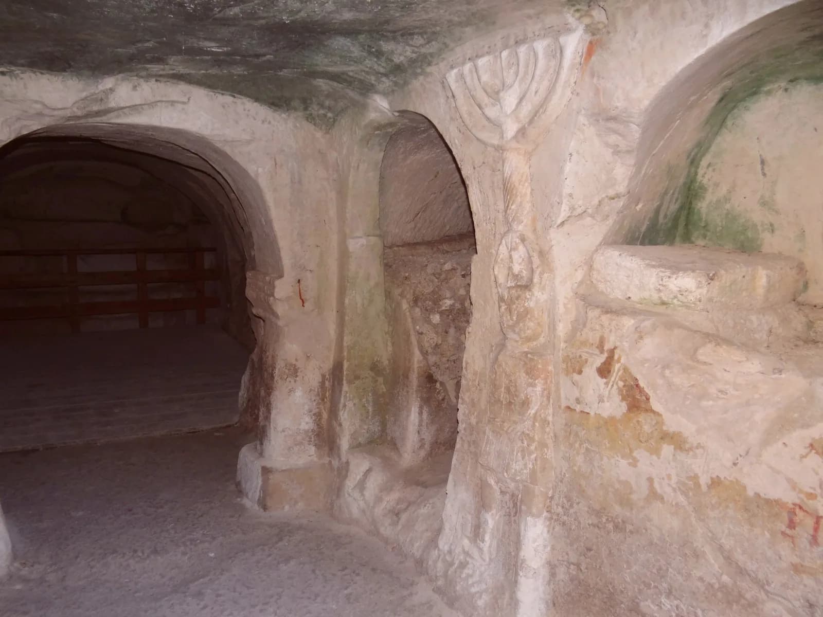 תבליט הלוחם ועל ראשו מנורה, בין פתח חדר קבורה לקבר מקמר המעוטר בקונכייה