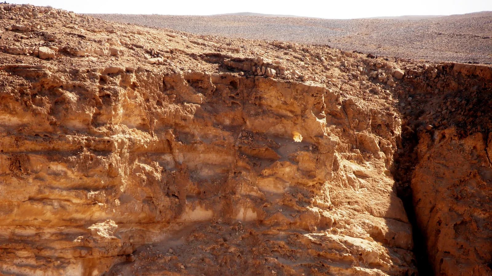 מצוק הגיר בהר כרכום עם פתח המערה הקטן המואר בזוהר "הסנה הבוער"